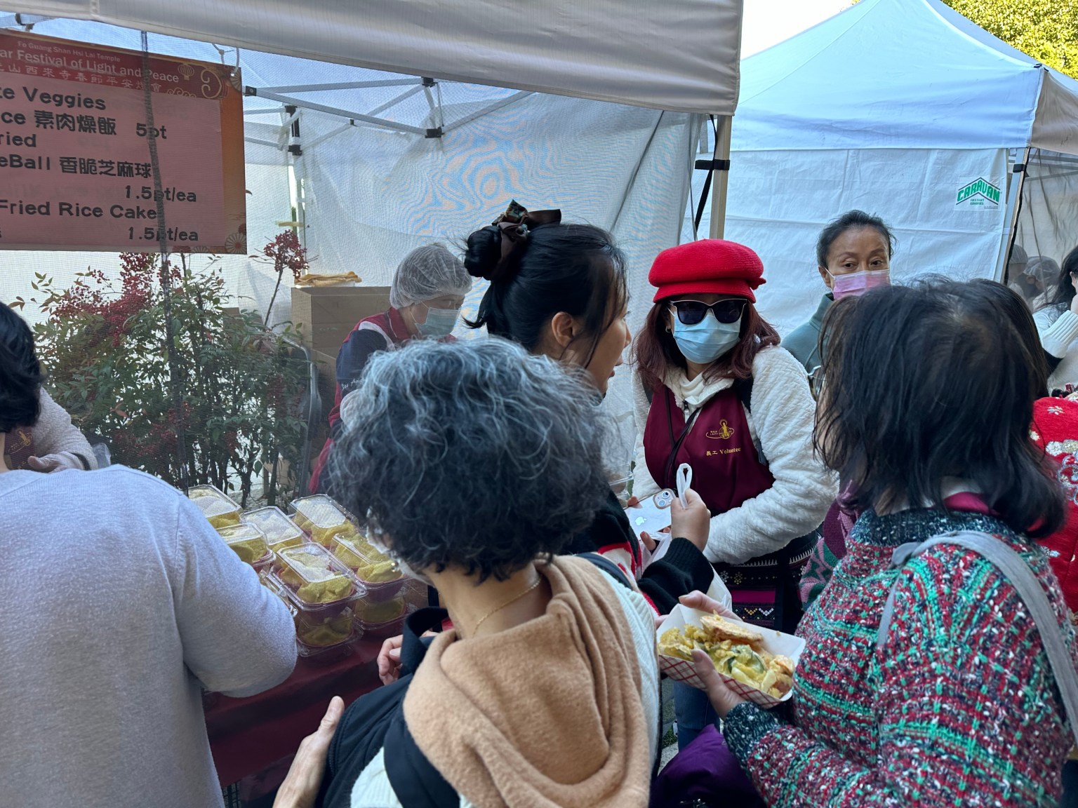 廖遠清師姐在攤位前介紹食物給經過的訪客