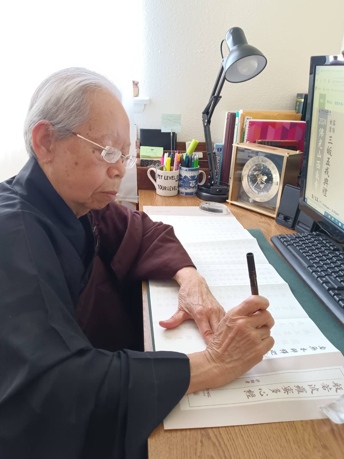 會員李素珍在家穿著海青縵衣，同步抄寫心經