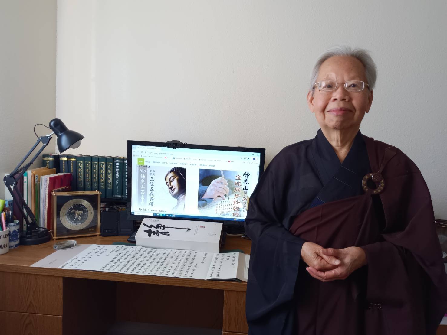 會員李素珍在家穿著海青縵衣，同步抄寫心經