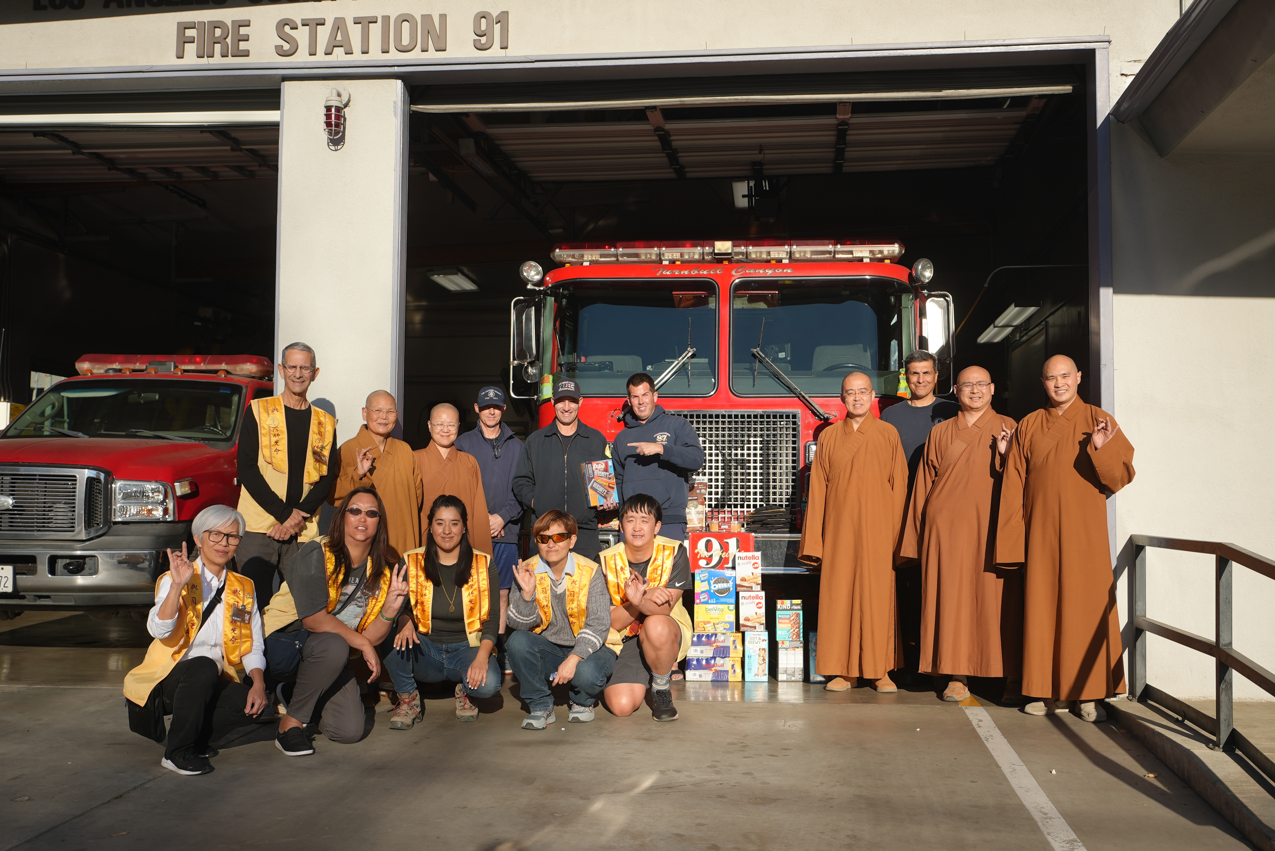 西來寺住持慧東法師(右三)帶領監院依宣法師(後排左二)、慧澤法師(右二)、慧澄法師(右一)及西來分會會員與洛杉磯郡消防局第91消防站4位打火英雄合影。