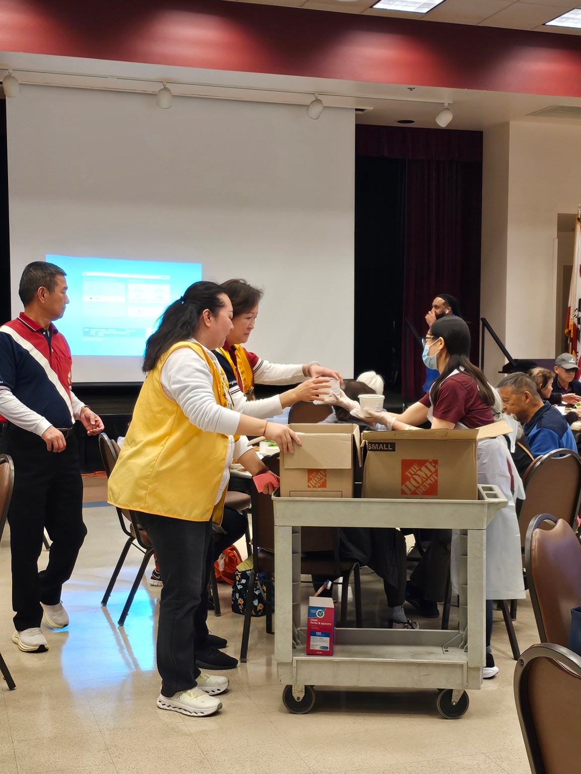 核桃老人中心工作人员Tiffany Pranajasa（右二) 協助分會會員將臘八粥一一送到長者們的手中