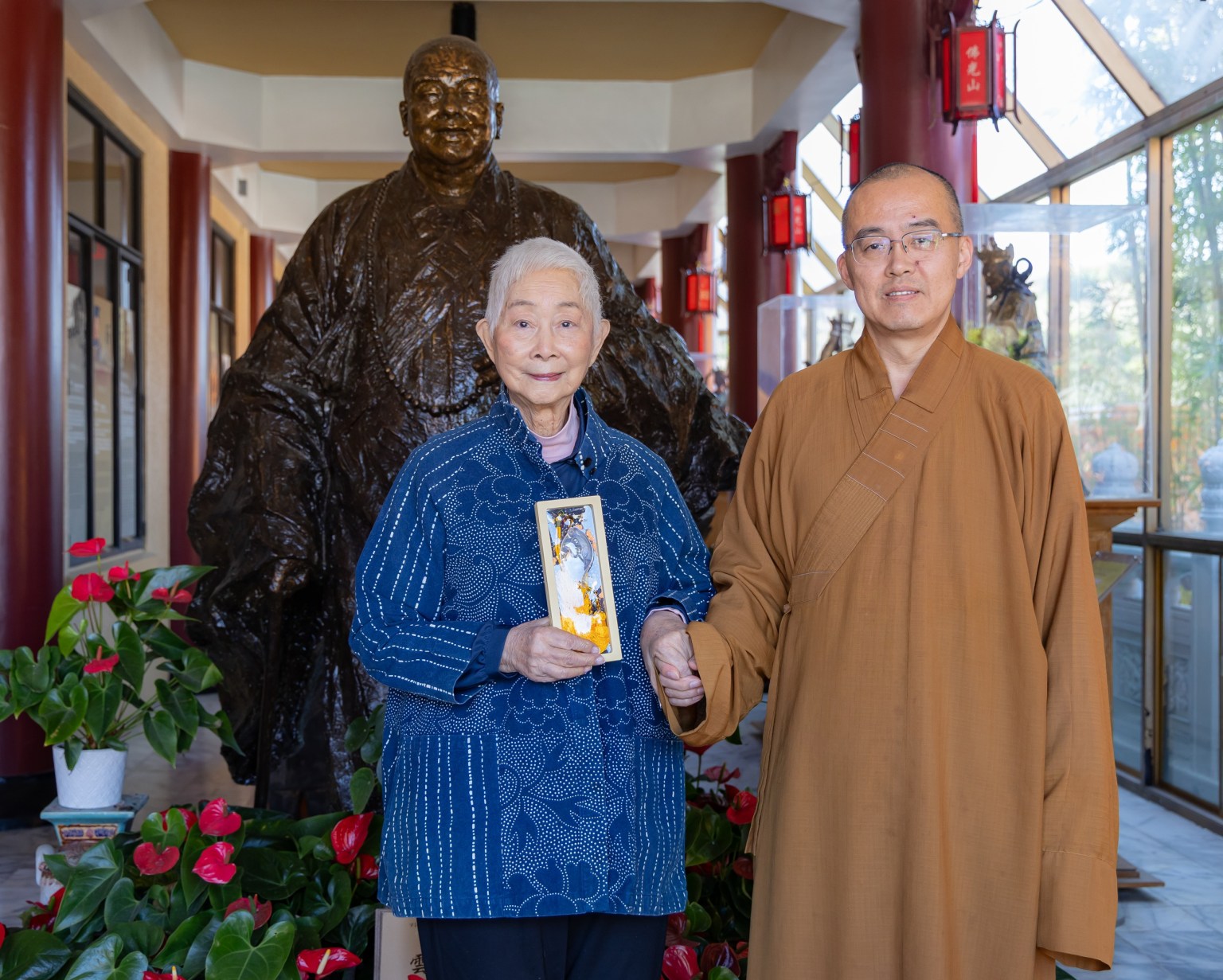 住持慧東法師特地致贈觀音吊飾給盧燕，並於大師銅像合影。