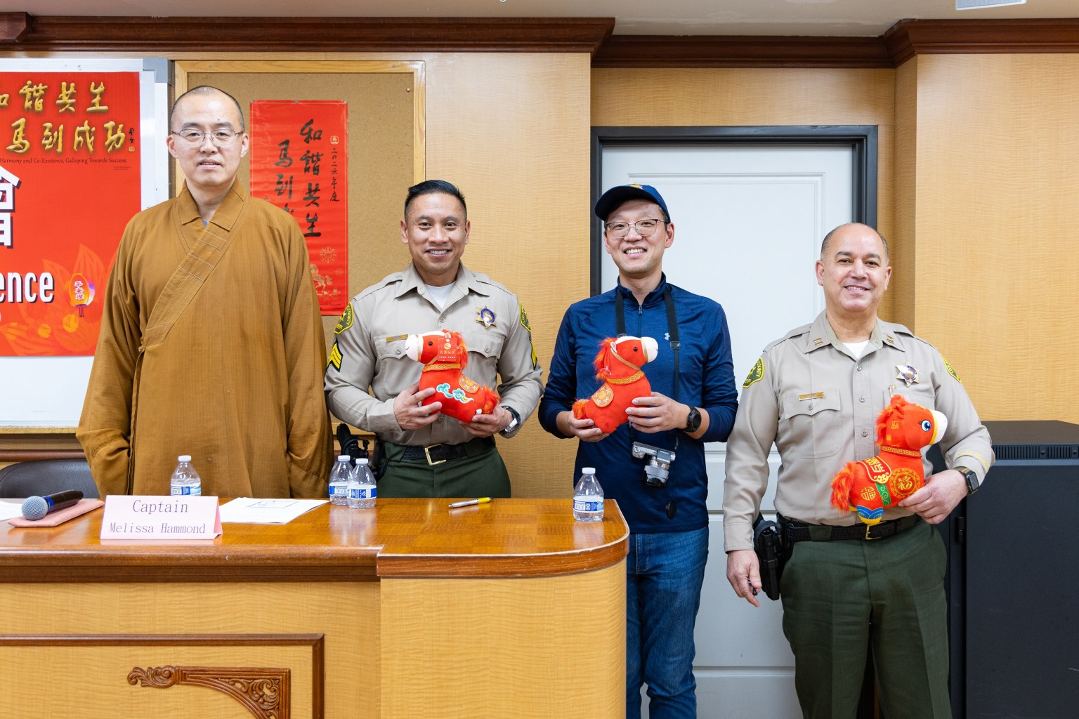 Police officers and members of the media receive Year of the Horse plush mascots and pose for a photo with Venerable Huidong (left).