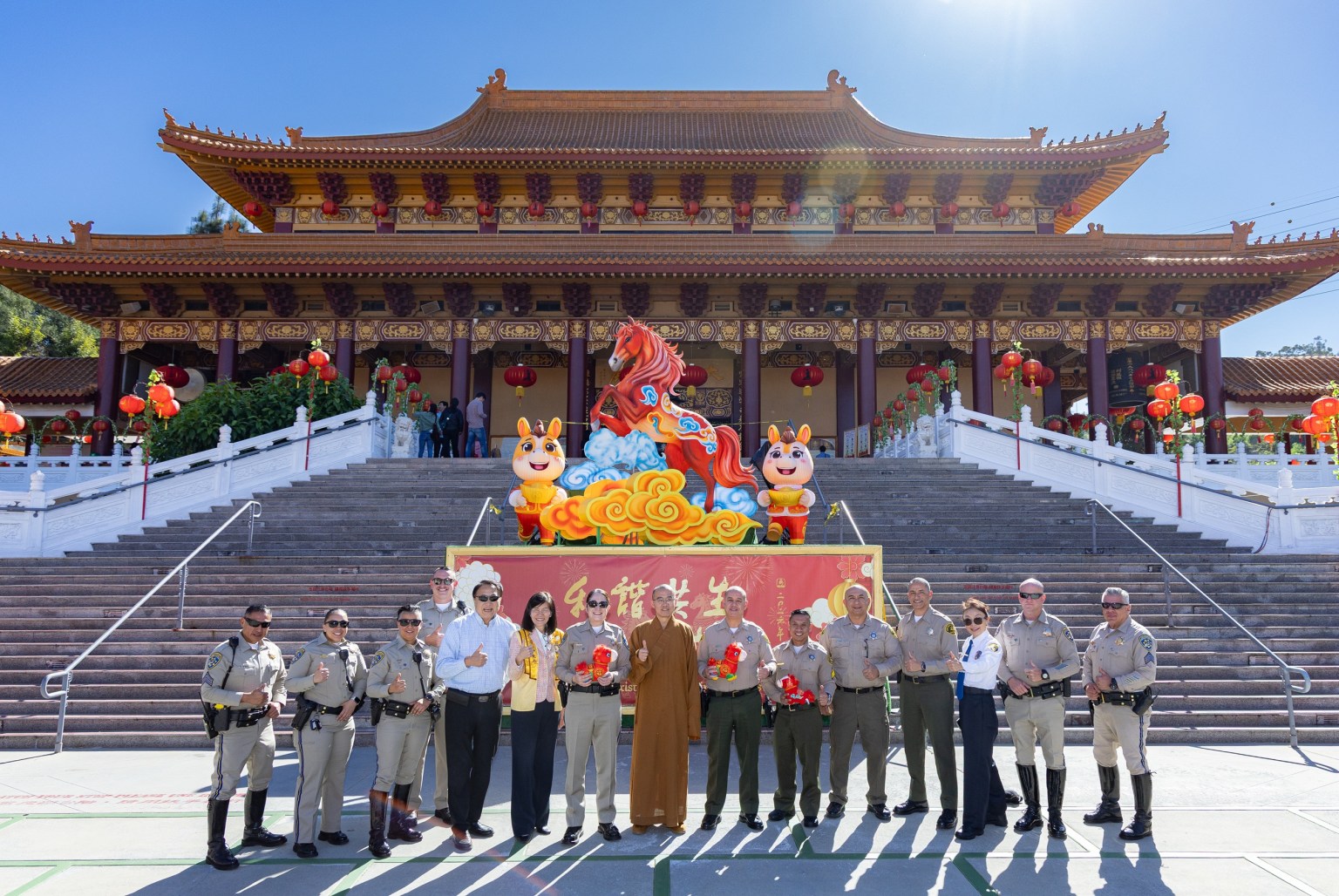 Venerable Huidong (center), BLIA Los Angeles Chapter President Tsai Yueh-chin (6th from left), Commander Melissa Hammond (7th from left) and her team, Chief Glenn Emery (7th from right) and his team, and Kenny Chang pose for a group photo in front of the Year of the Fire Horse lantern on the Path to Buddhahood.