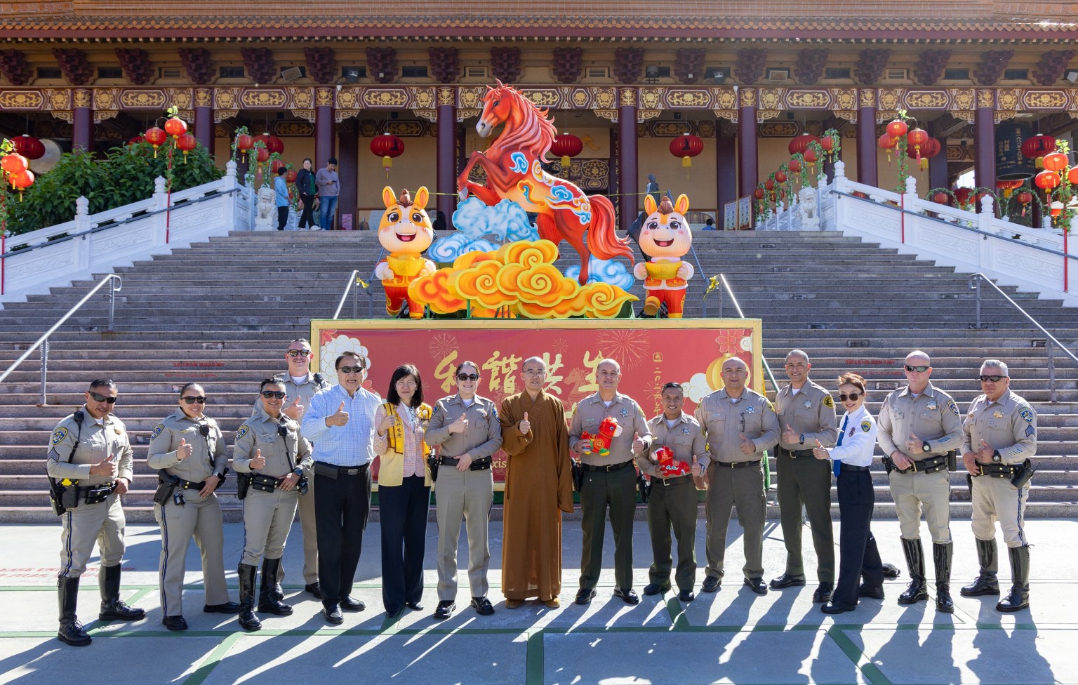 Venerable Huidong (center), President Echo Tsai (6th from left), Commander Melissa Hammond (7th from left) and her team, Chief Glenn Emery (7th from right) and his team, and Kenny Chang pose for another group photo in front of the Year of the Fire Horse lantern on the Path to Buddhahood.